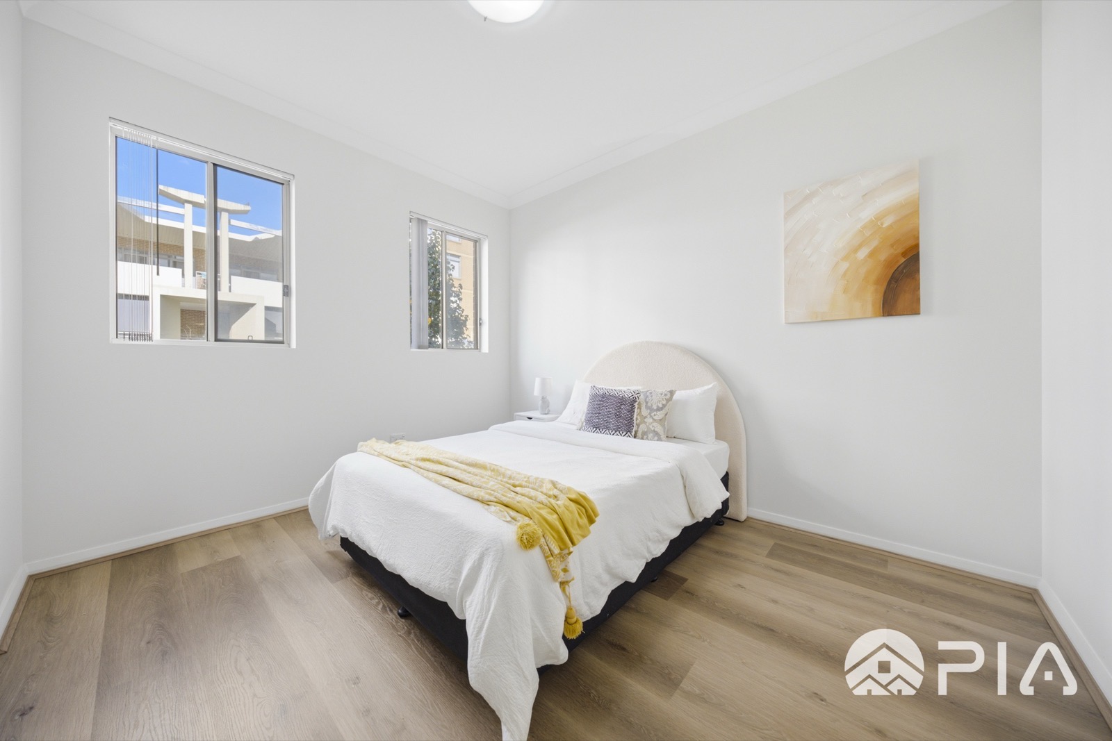 Airbnb bedroom with arched bouclé headboard and yellow throw