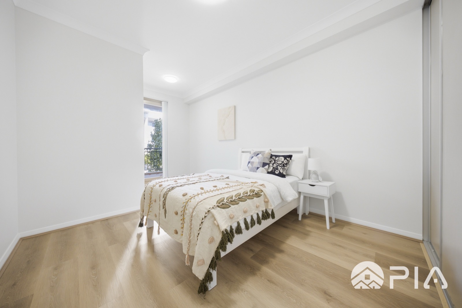Airbnb bedroom styled with tasselled throw and bedside table