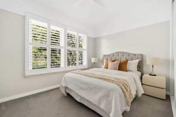 Bedroom styled with plantation shutters and mustard cushions