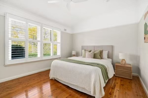 Bedroom styled with plantation shutters and green throw