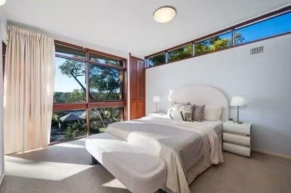 Bedroom with timber windows and leafy view